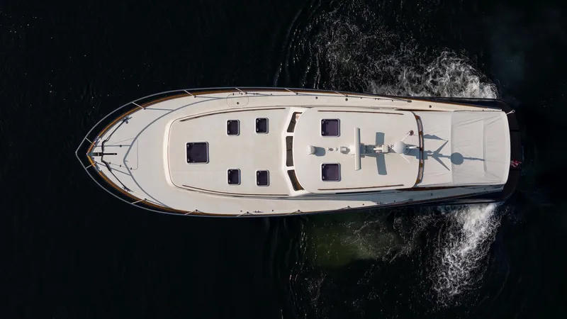 Chic Yacht Photos Pics 2003 Hinckley Talaria 44 Express yacht cruising on dark water, aerial view.