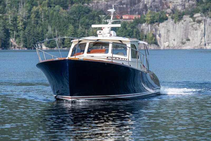 Chic Yacht Photos Pics 2003 Hinckley Talaria 44 Express cruising on a serene lake with forested cliffs.