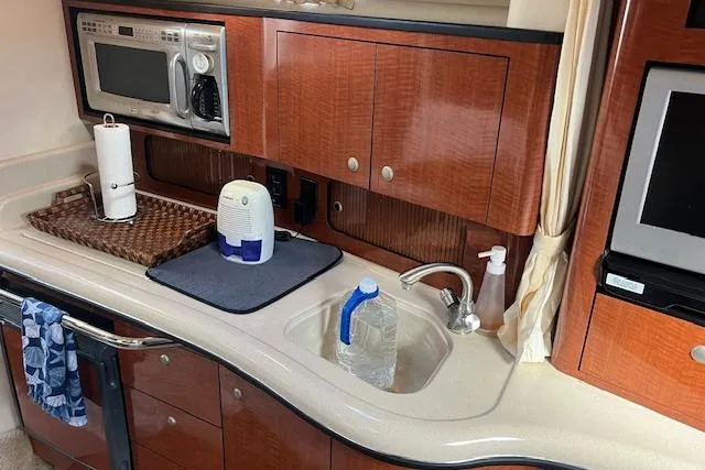 H20 Kiss Yacht Photos Pics 2005 Searay 320 yacht kitchen with microwave, sink, and wooden cabinets.