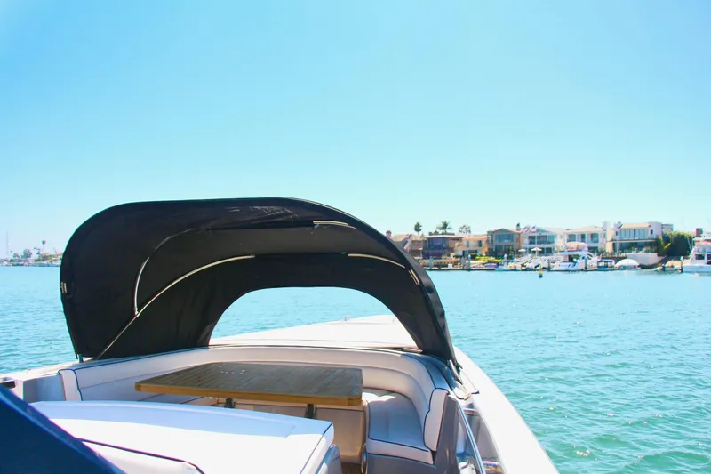  Yacht Photos Pics Maori 50 boat (2017) with canopy on calm water near coastal homes.