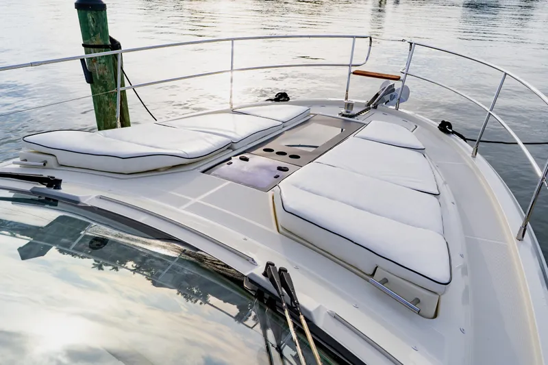 Nauti Obsession Yacht Photos Pics Luxurious 2015 Monte Carlo MC5 yacht with cushioned deck, docked by calm waters.