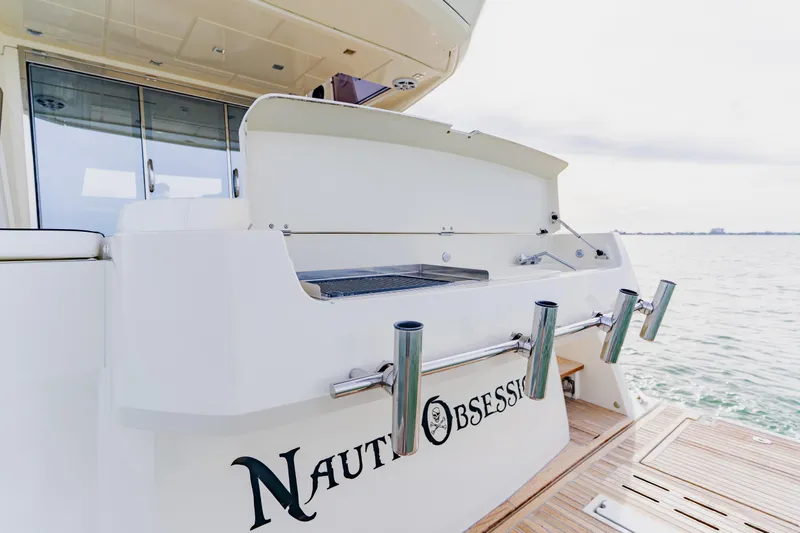 Nauti Obsession Yacht Photos Pics Sleek 2015 Monte Carlo MC5 yacht with fishing rod holders, named "Naut Obsession," on calm waters.