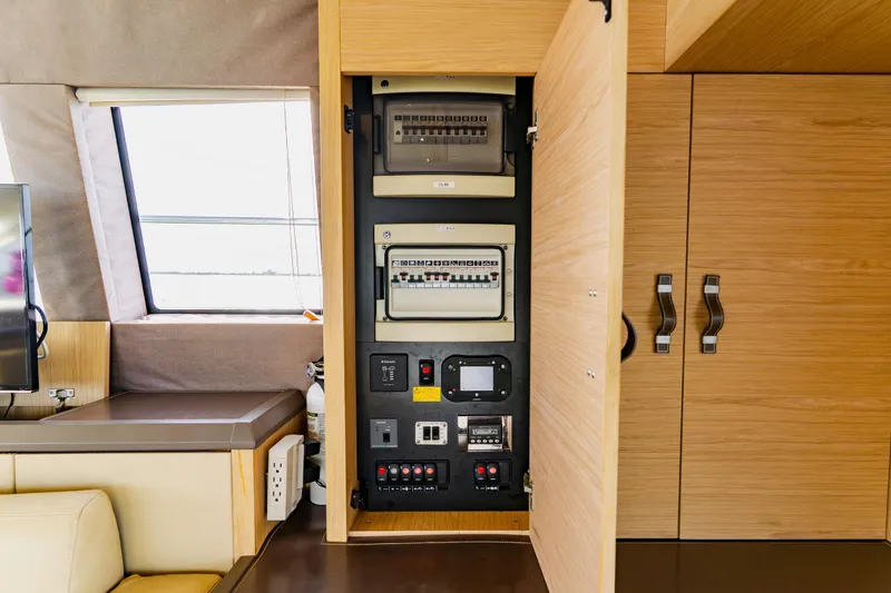 Nauti Obsession Yacht Photos Pics Electrical panel inside 2015 Monte Carlo MC5 yacht, featuring modern wooden cabinetry.