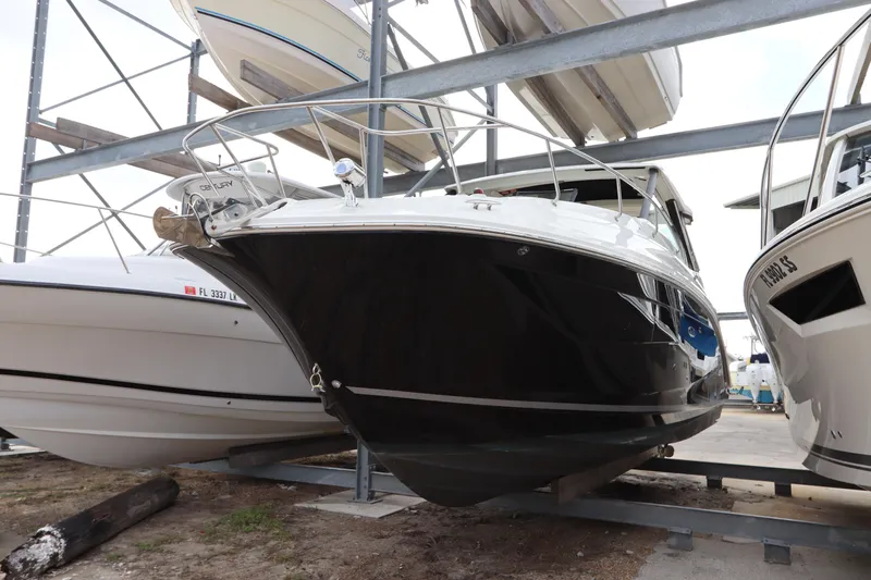  Yacht Photos Pics 2019 Sea Ray Sundancer 320 boat in storage, black hull, docked between other boats.