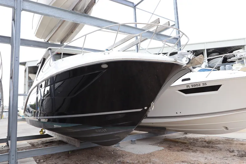  Yacht Photos Pics 2019 Sea Ray Sundancer 320 boat in storage, black hull, docked alongside another vessel.