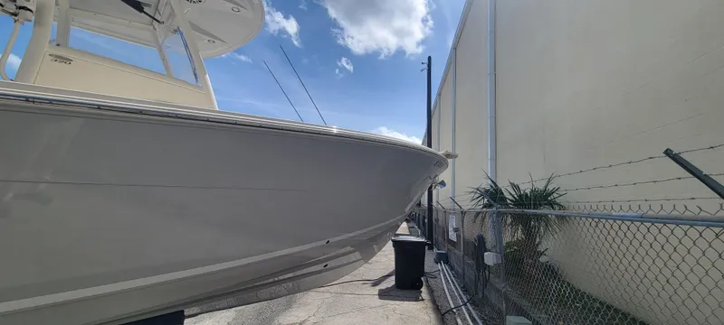  Yacht Photos Pics 2020 Cobia 320 Center Console boat docked beside a fence under a blue sky.