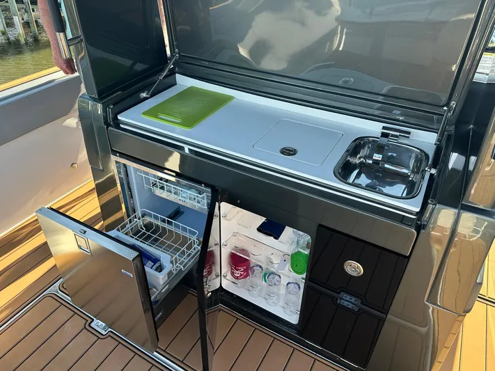 Trouble Maker Yacht Photos Pics Outdoor kitchenette on 2022 Schaefer V33 yacht with sink, cutting board, and fridge.