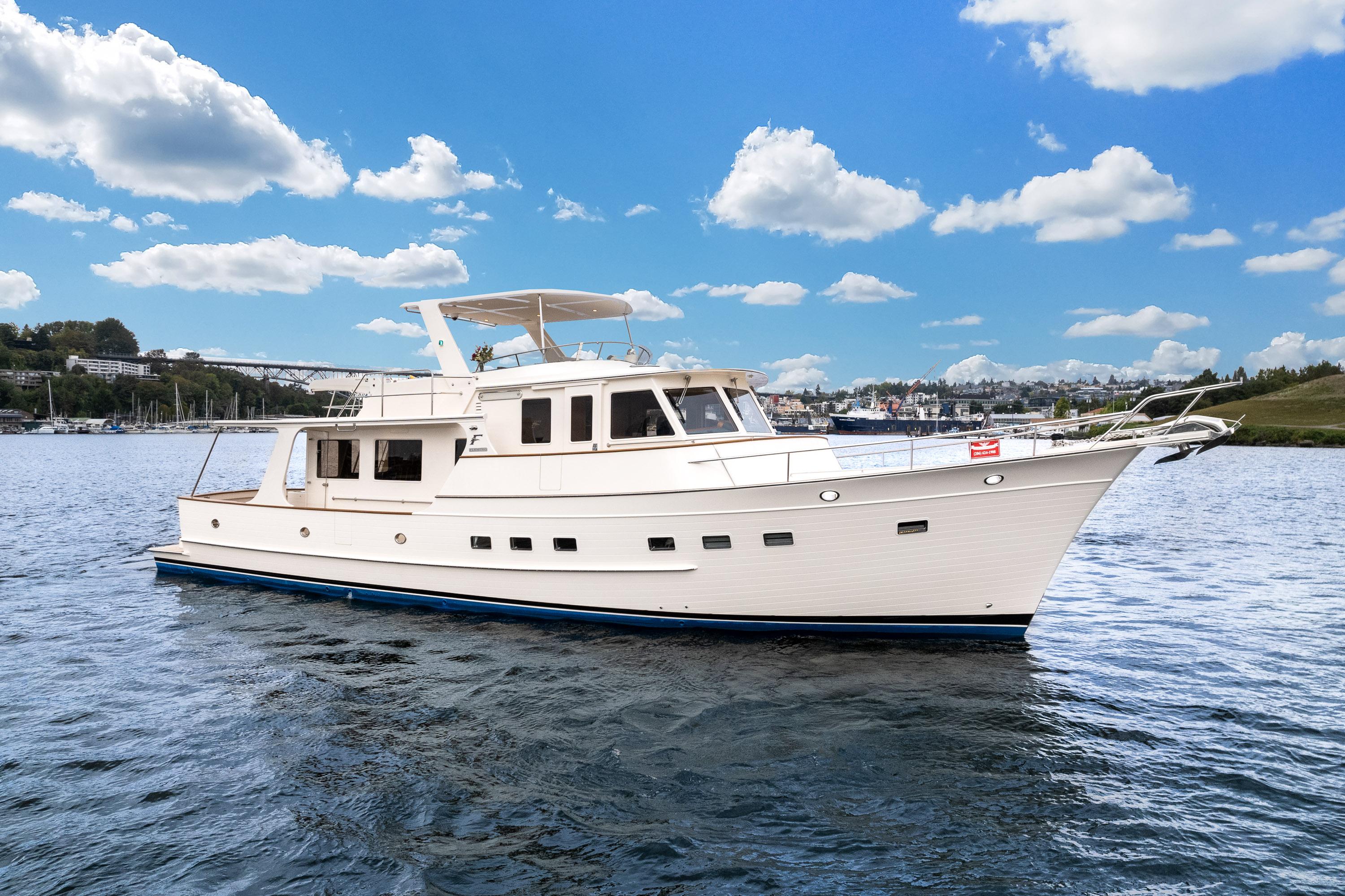 2024 Fleming 58 Pilothouse yacht cruising on a calm, scenic waterway under a blue sky.