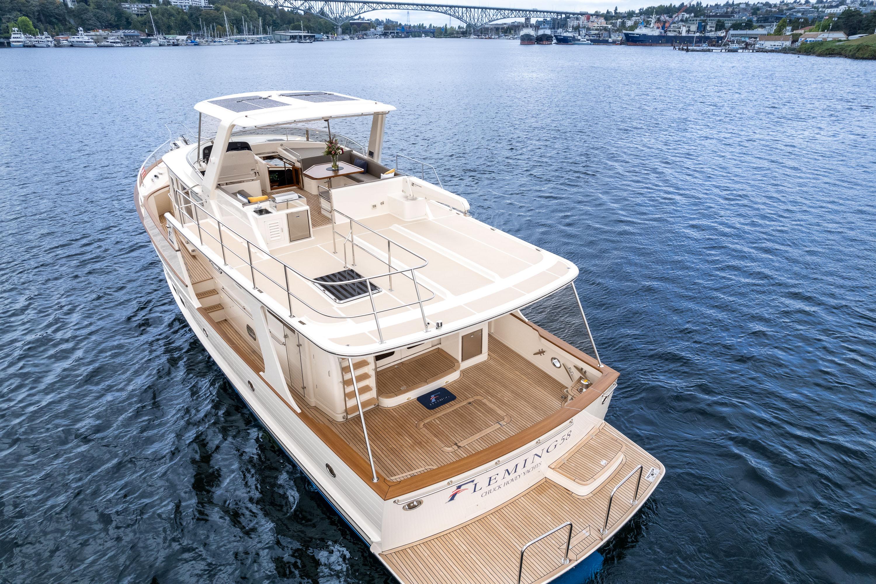 2024 Fleming 58 Pilothouse yacht cruising on a serene lake with scenic bridge view.