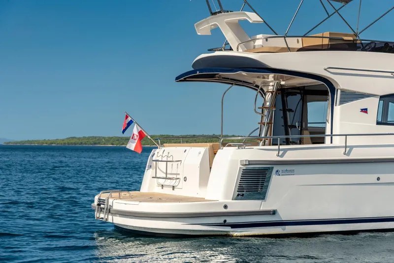  Yacht Photos Pics Nimbus 405 Flybridge 2026 yacht on calm water, featuring sleek design and flags.