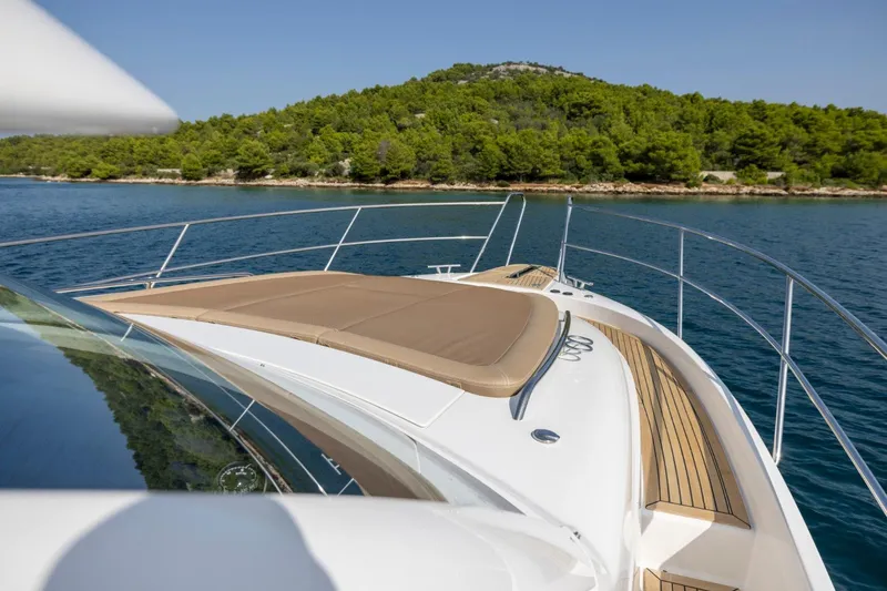  Yacht Photos Pics Luxurious 2026 Nimbus 405 Flybridge yacht cruising near a lush, green island.
