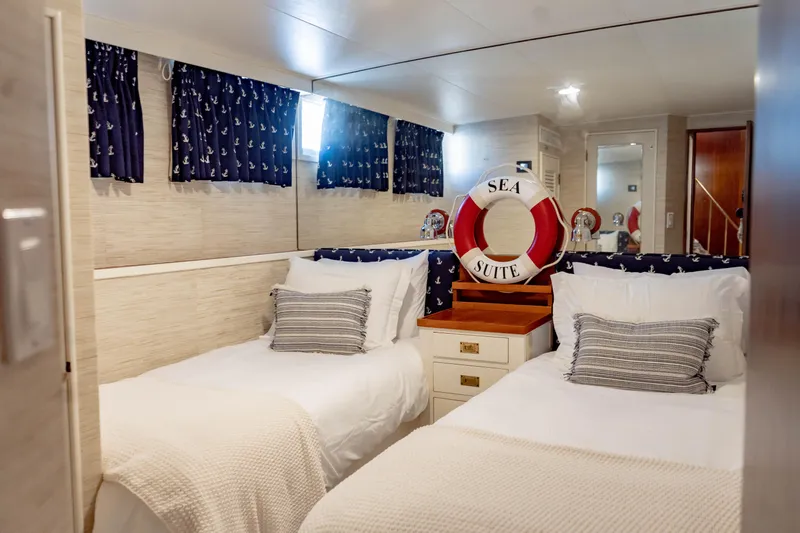 Sea Suite Yacht Photos Pics Twin beds in a cozy yacht cabin with nautical decor, featuring a "Sea Suite" lifebuoy.