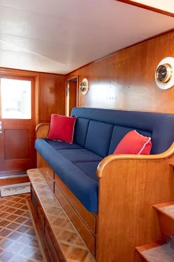Sea Suite Yacht Photos Pics Luxurious 1974 Burger 67 yacht interior with blue sofa, red cushions, and wooden paneling.