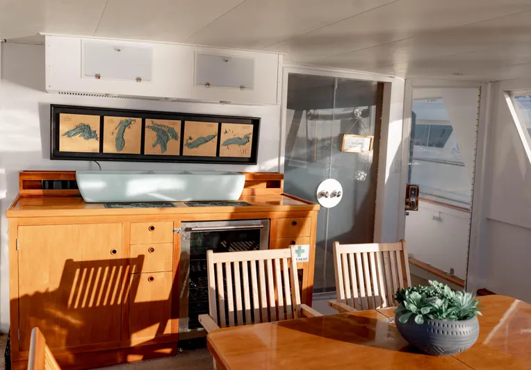Sea Suite Yacht Photos Pics Luxurious yacht interior with wooden furniture, framed maps, and a decorative plant.