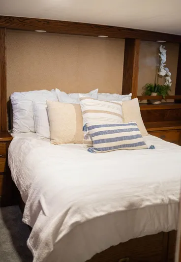 Sea Suite Yacht Photos Pics Cozy bedroom with white bedding, striped pillows, and wooden accents on a 1974 Burger 67 yacht.