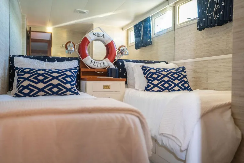 Sea Suite Yacht Photos Pics Luxurious yacht bedroom with nautical decor, featuring twin beds and a "Sea Suite" life preserver.