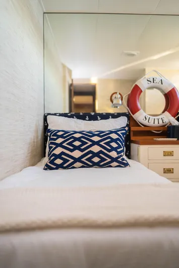 Sea Suite Yacht Photos Pics Cozy yacht bedroom with nautical decor, featuring patterned pillow and "Sea Suite" lifebuoy.
