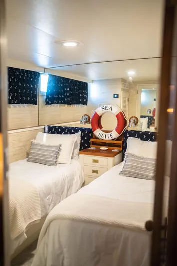 Sea Suite Yacht Photos Pics Cozy yacht cabin with twin beds, nautical decor, and "Sea Suite" lifebuoy.