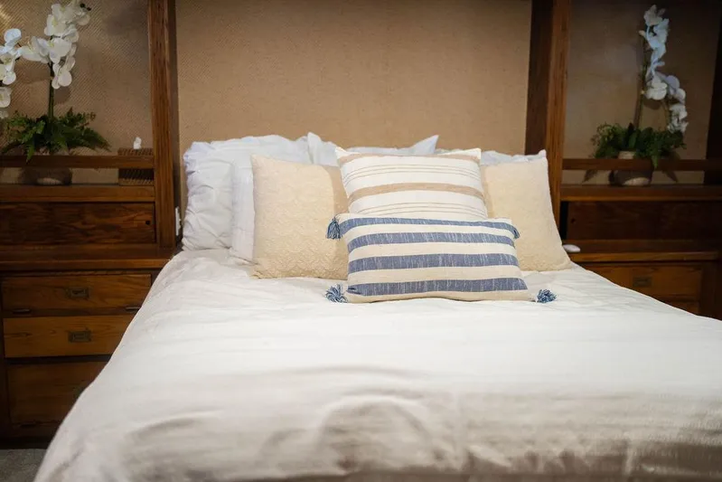 Sea Suite Yacht Photos Pics Cozy bed with striped pillows and wooden headboard, featuring elegant floral decor.