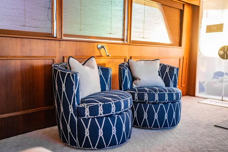Sea Suite Yacht Photos Pics Two blue patterned chairs with cushions in a wooden-paneled room, aboard a 1974 Burger 67 yacht.