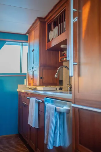 Sea Suite Yacht Photos Pics Wooden kitchen interior on a 1974 Burger 67 yacht, featuring cabinets and a window view.