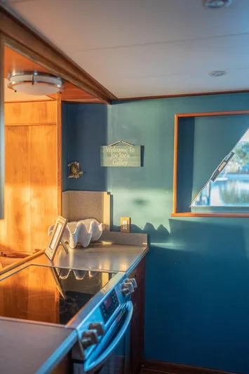 Sea Suite Yacht Photos Pics Cozy boat kitchen with blue walls, stove, and decorative shell.