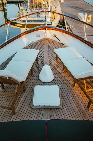 Sea Suite Yacht Photos Pics Bow of a 1974 Burger 67 yacht with wooden deck and white lounge chairs.