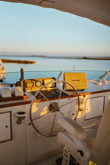 Sea Suite Yacht Photos Pics Helm of a 1974 Burger 67 yacht with Garmin navigation, overlooking serene waters at sunset.