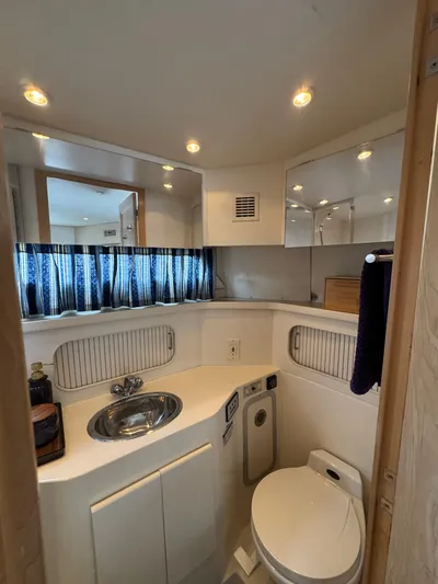 Y Knot Yacht Photos Pics 1997 Carver 405 Aft Cabin bathroom with sink, toilet, and mirror.