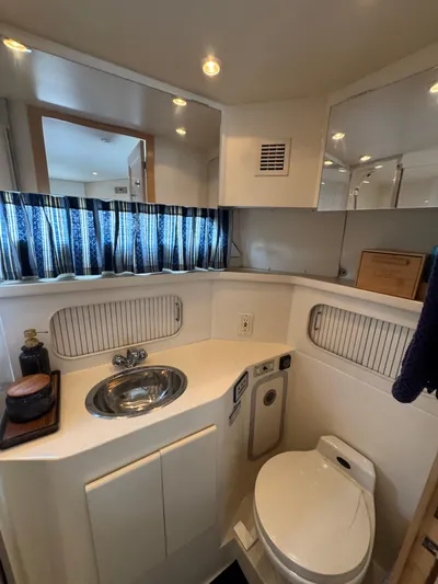 Y Knot Yacht Photos Pics 1997 Carver 405 Aft Cabin bathroom with sink, toilet, and mirror.