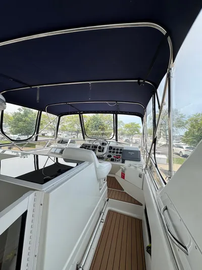 Y Knot Yacht Photos Pics 1997 Carver 405 Aft Cabin yacht interior with helm, blue canopy, and wood flooring.
