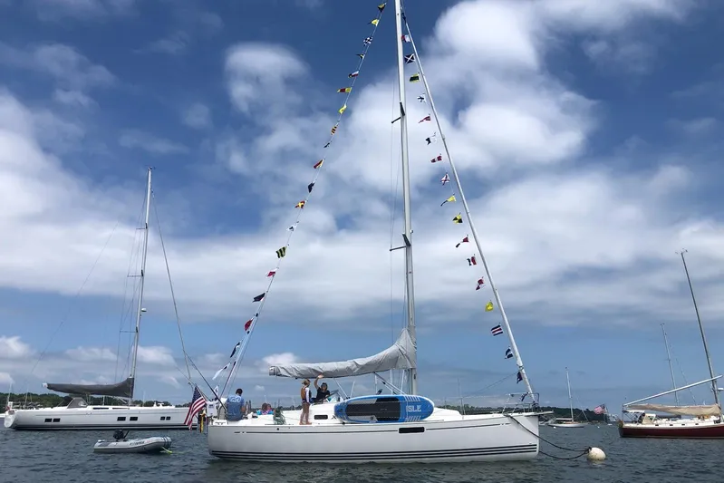  Yacht Photos Pics 2015 X-Yachts Xc-35 sailboat with colorful flags, anchored in a scenic harbor.