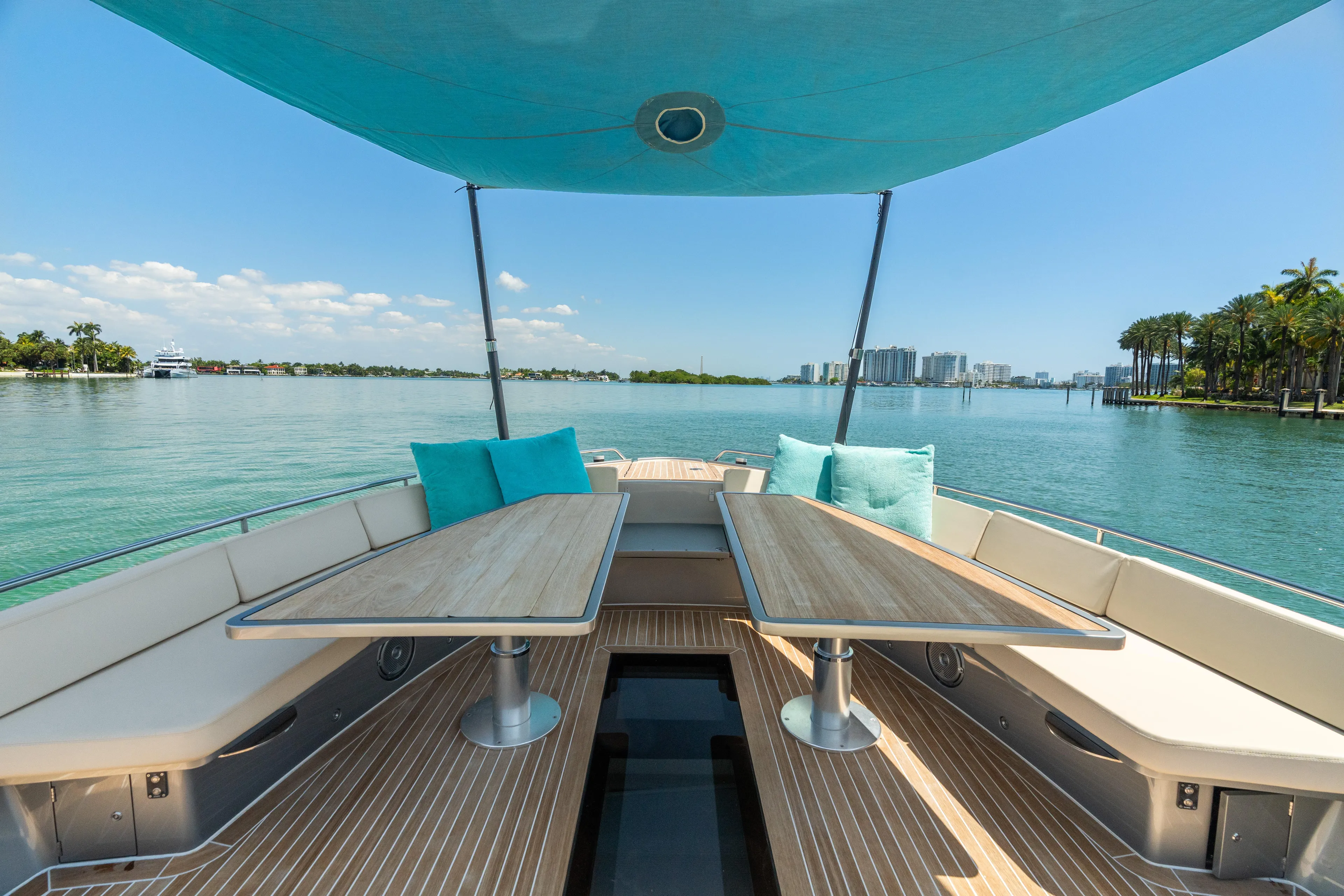 Yanina Yacht Photos Pics Luxurious 2019 CNM Continental 54T yacht deck with tables, overlooking serene waters and cityscape.