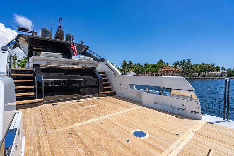 Snack Money Yacht Photos Pics 2023 Bluegame BG 72 yacht with spacious deck, docked by a scenic waterfront.