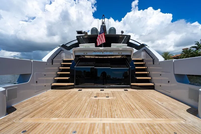 Snack Money Yacht Photos Pics 2023 Bluegame BG 72 yacht deck with stairs, American flag, and cloudy sky backdrop.