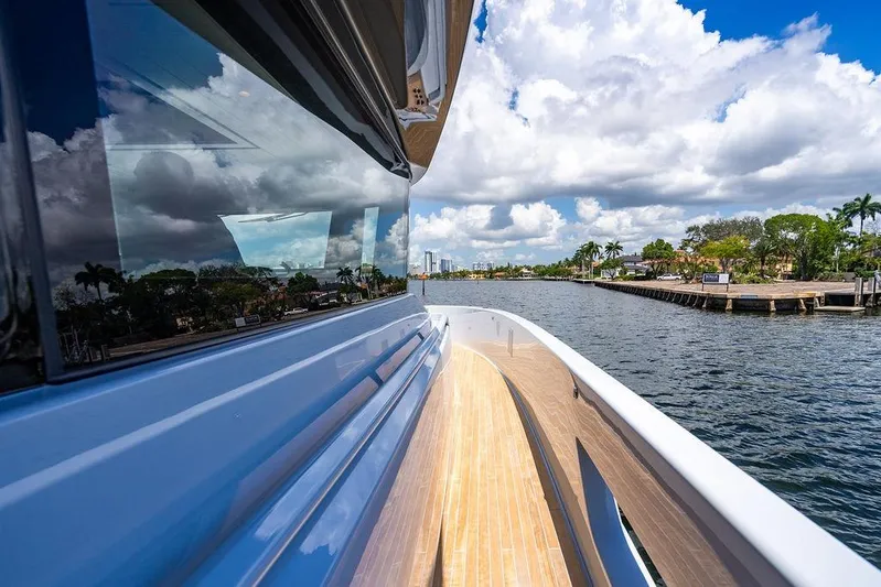 Snack Money Yacht Photos Pics 2023 Bluegame BG 72 yacht cruising on a scenic waterway under a partly cloudy sky.