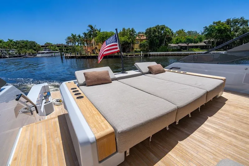 Snack Money Yacht Photos Pics Luxurious 2023 Bluegame BG 72 yacht with sunbed, American flag, and scenic waterfront view.
