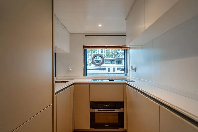 Snack Money Yacht Photos Pics Modern kitchen interior on 2023 Bluegame BG 72 yacht, featuring sleek cabinetry and window view.