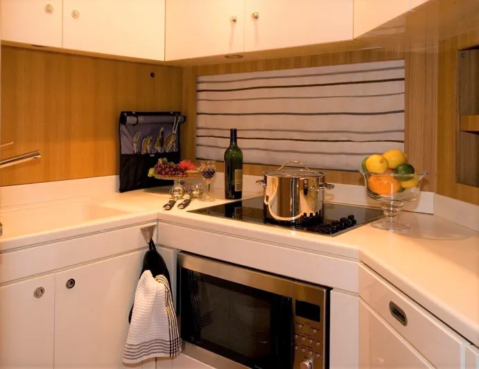 Bon Vivant Yacht Photos Pics Modern kitchen in a 2004 Riva Splendida yacht with stove, microwave, and fruit bowl.