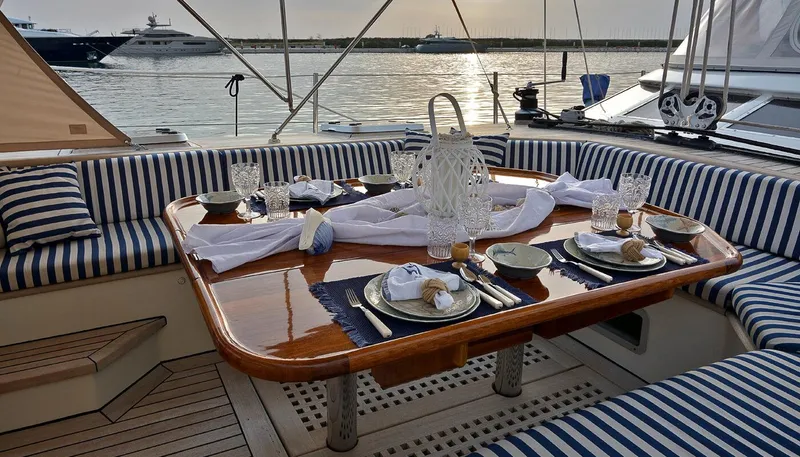 Wind Of Change Yacht Photos Pics Elegant dining setup on a 1988 Brooke Marine Motorsailer yacht with striped seating and waterfront view.