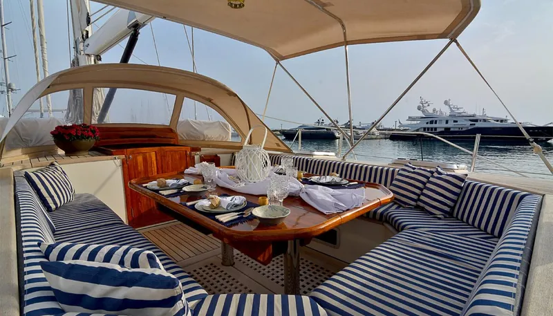 Wind Of Change Yacht Photos Pics Luxurious 1988 Brooke Marine Motorsailer with elegant outdoor dining area and striped seating.