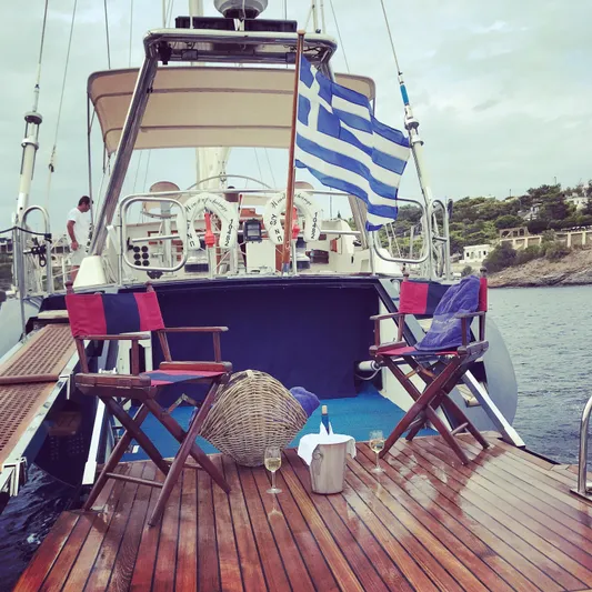 Wind Of Change Yacht Photos Pics 1988 Brooke Marine Motorsailer with Greek flag, deck chairs, and wine setup.