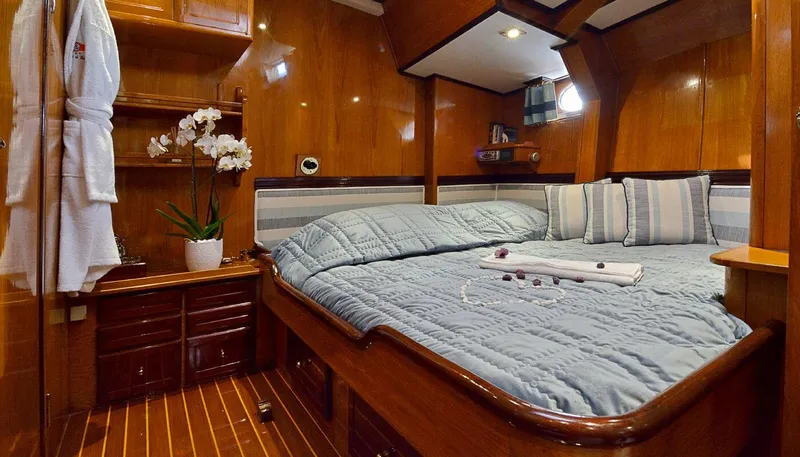 Wind Of Change Yacht Photos Pics Luxurious cabin interior of 1988 Brooke Marine Motorsailer with wooden finishes and cozy bedding.