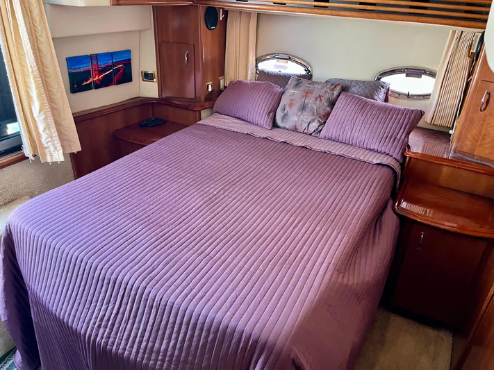 One In A Million Yacht Photos Pics Luxurious bedroom interior of 2005 Carver 444 yacht with purple bedding and wooden accents.