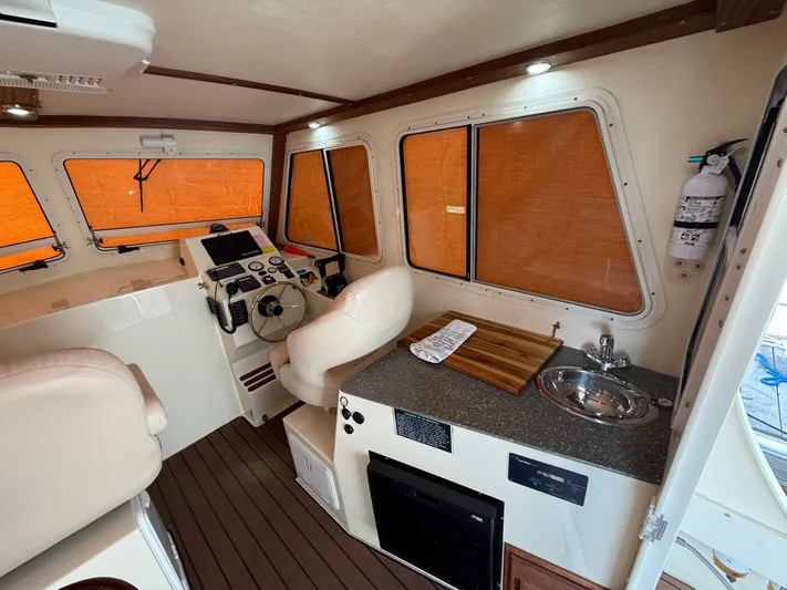 Rhode Waves Yacht Photos Pics Interior of a 2018 Eastern 27 Islander Hardback boat with helm and kitchenette.