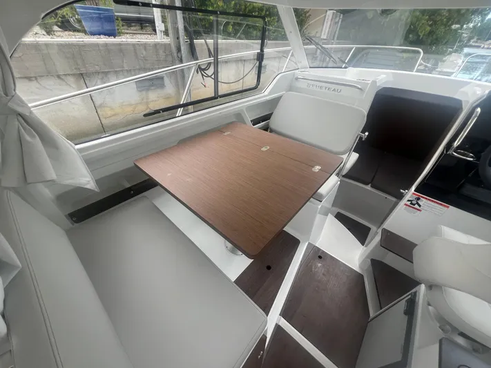  Yacht Photos Pics Interior of 2025 Beneteau Antares 8 boat with seating and wooden table.