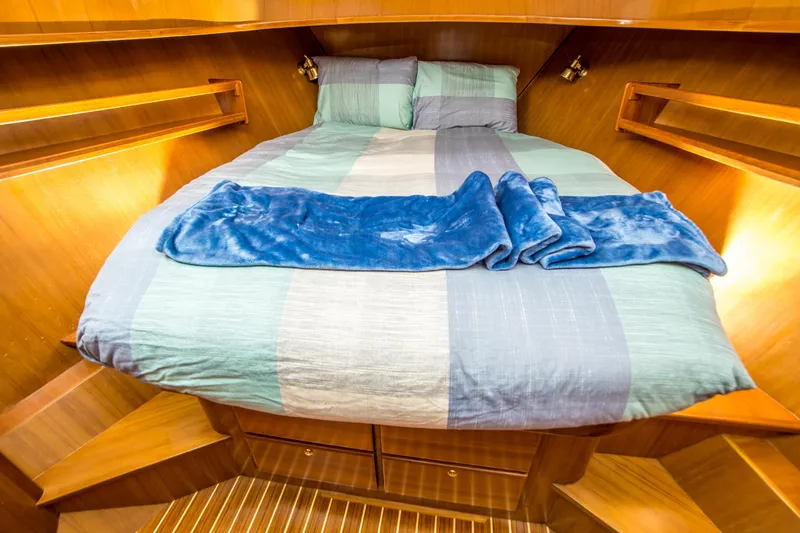 Papagayo Yacht Photos Pics Cozy cabin interior of 2008 North Pacific 43 Pilothouse with striped bedding and wooden finish.