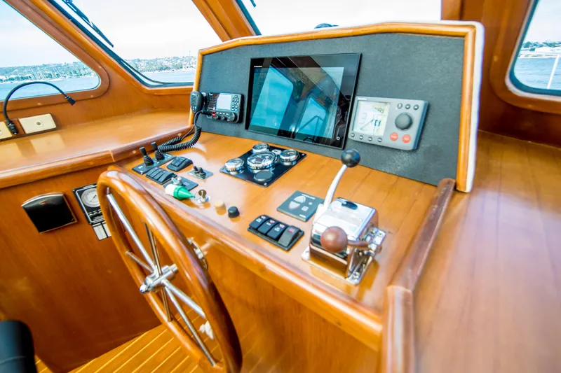 Papagayo Yacht Photos Pics Pilothouse interior of 2008 North Pacific 43, featuring navigation controls and wooden steering wheel.
