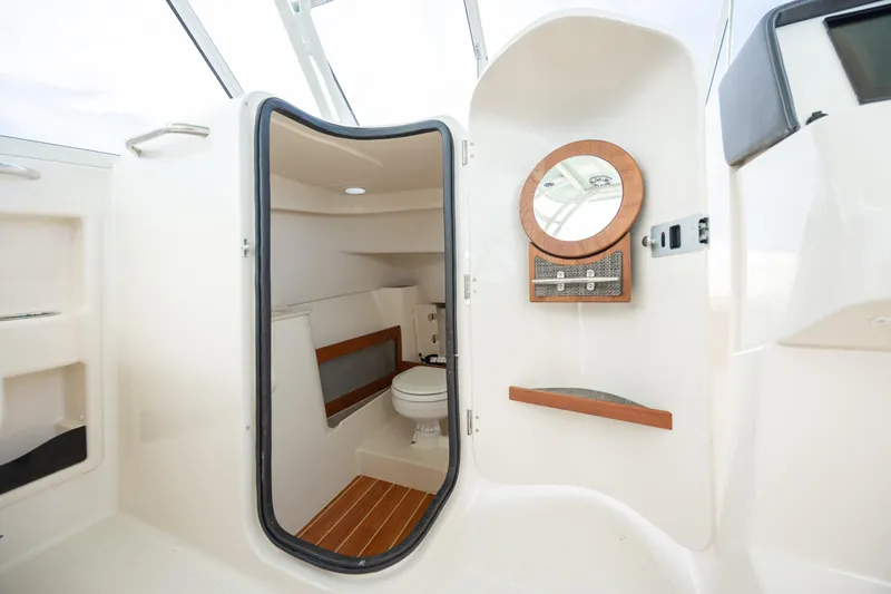  Yacht Photos Pics 2023 Grady-White Freedom 285 boat interior with compact bathroom and wooden accents.