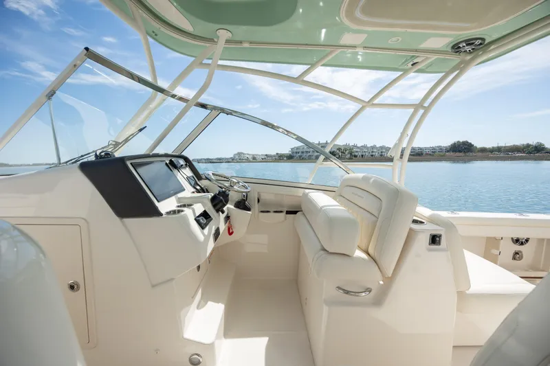  Yacht Photos Pics 2023 Grady-White Freedom 285 boat interior with helm and seating, overlooking calm waters.